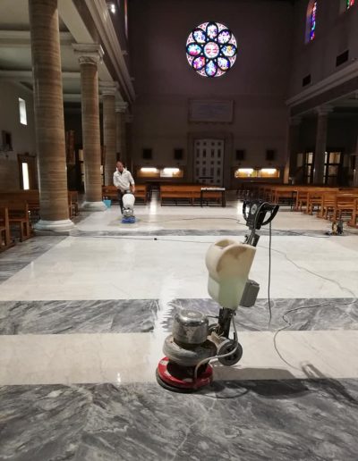 Pavimento in marmo scuro lucidato da Robur Servizi Srl all’interno di una chiesa, risultato finale brillante e uniforme.