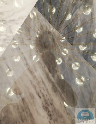 Dettaglio del pavimento in marmo lucidato con riflesso di un lampadario a sospensione, lavoro firmato Robur Servizi.